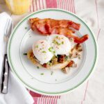 A serving of creamed mushrooms and poached eggs with a side of bacon on a serving plate.