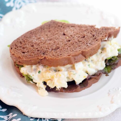 Herbed egg salad sandwich on a white serving plate.