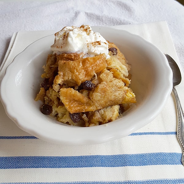 A serving of bread pudding with whipped cream in a small bowl.