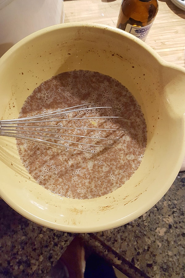 Milk, eggs, sugar, melted butter, cinnamon, vanilla, and salt in a bowl with a whisk.