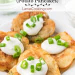 Boxty topped with sour cream and green onions on a white serving plate.
