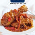 A plate of paprika chicken with red peppers and onions in a rich sauce, served on a white plate.