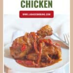 A plate of paprika chicken with red peppers in sauce, served on a white plate with a fork and napkin.