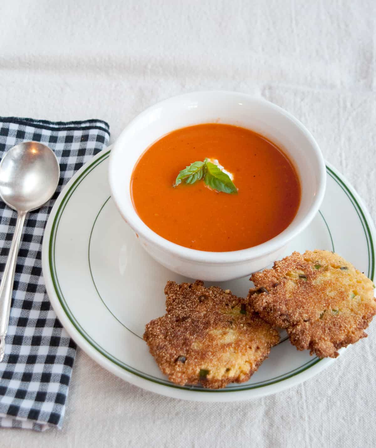 A bowl of tomato soup with cornmeal fritters on the side.