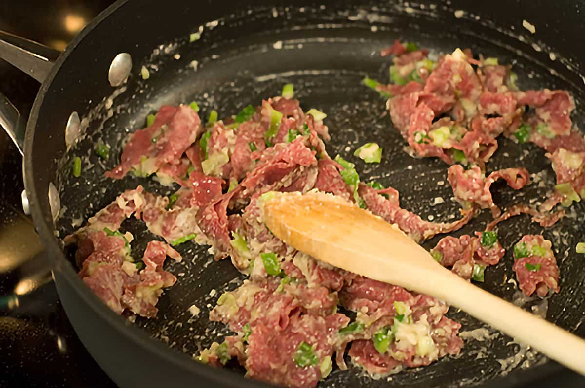 Flour stirred into the beef and onions in a skillet.