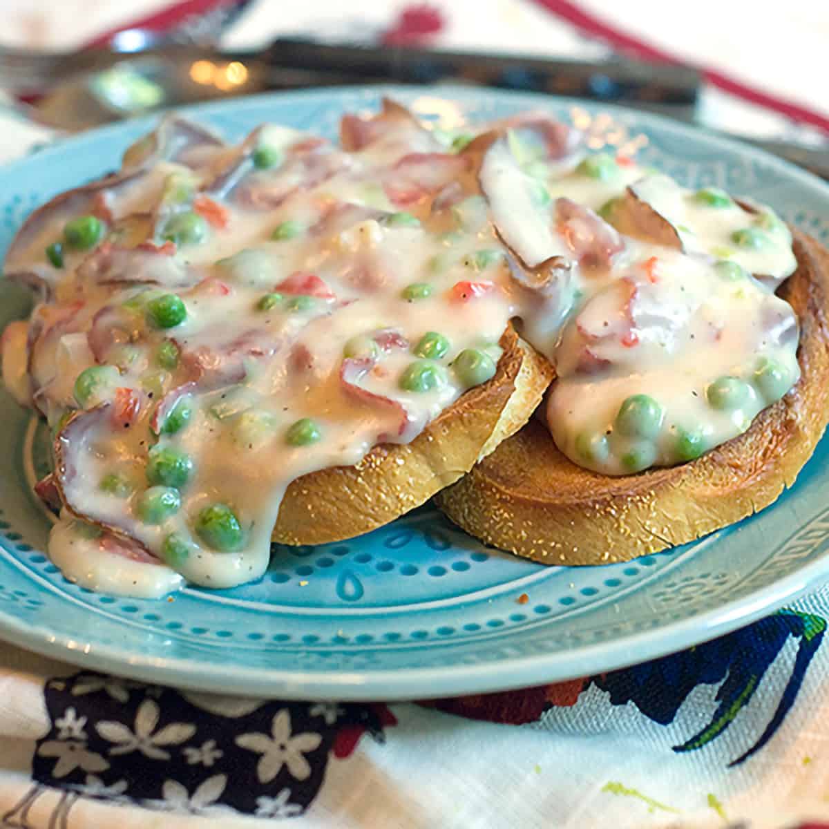 A serving of creamed chipped beef with peas over toast on a blue plate.