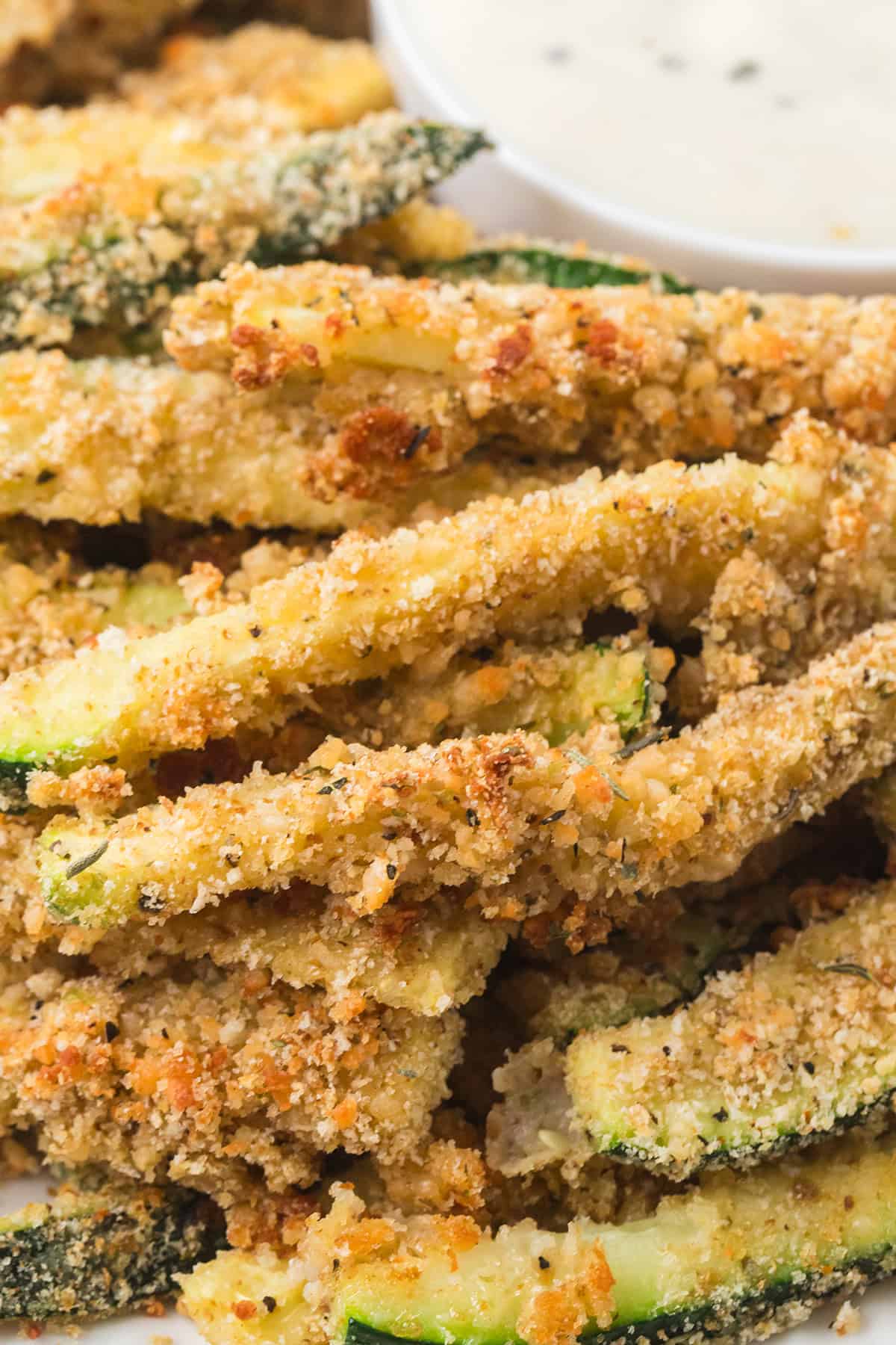 A plate filled with zucchini fries with dip on the side.