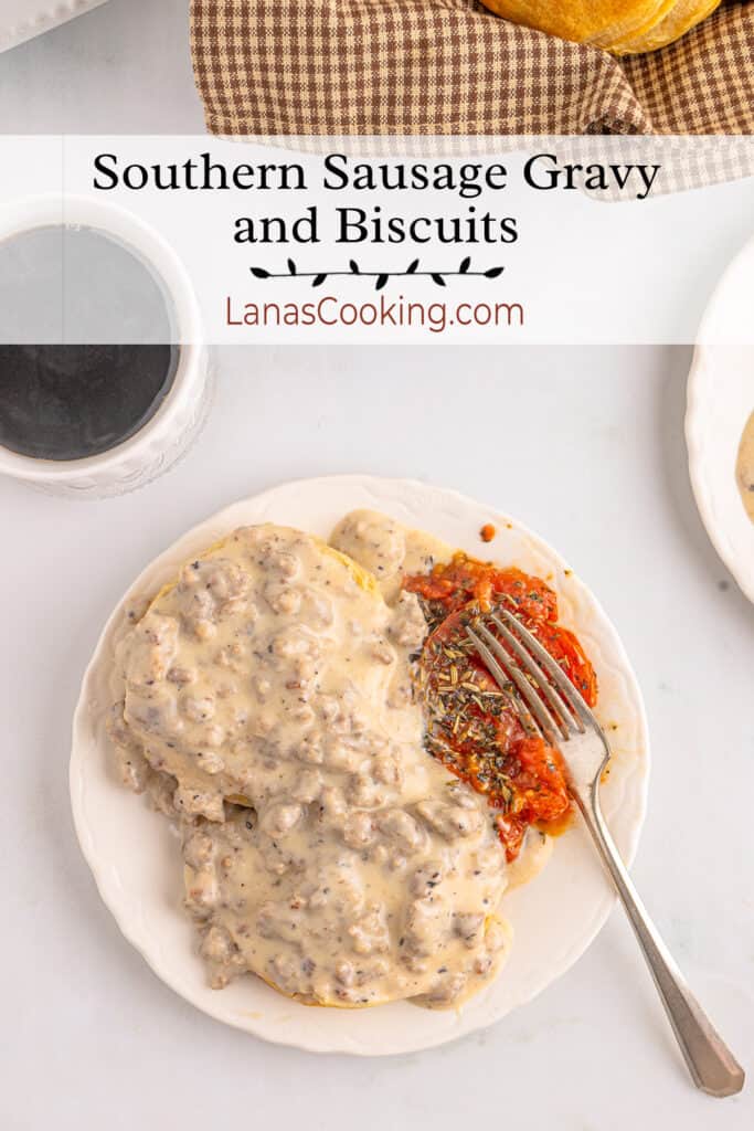 Sausage gravy and biscuits on a plate with baked tomatoes.
