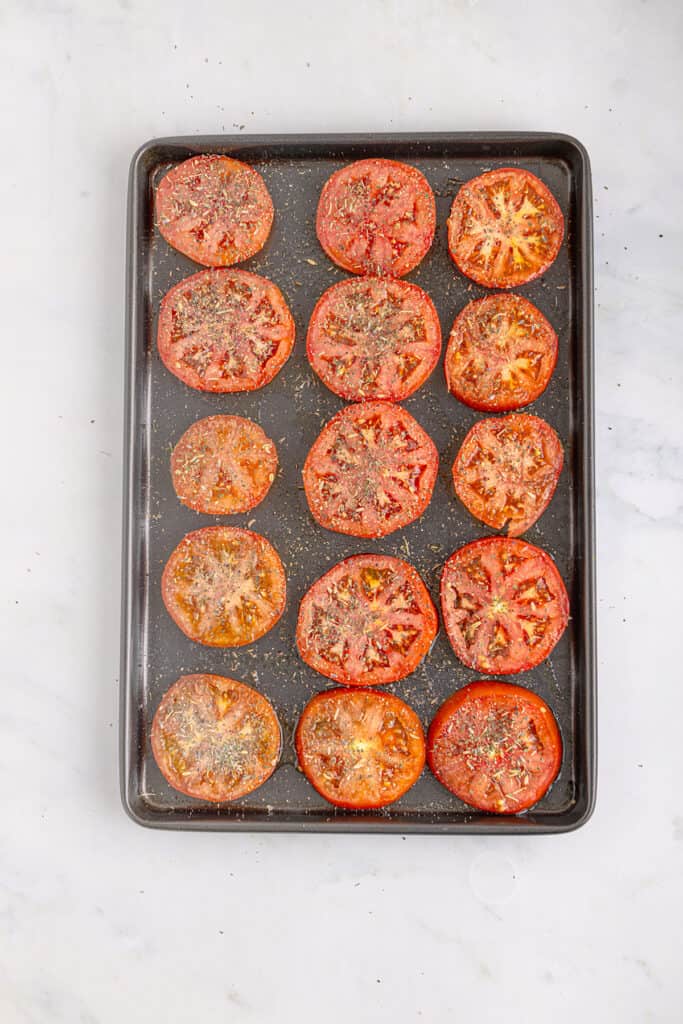 Tomato slices arranged on a baking pan.