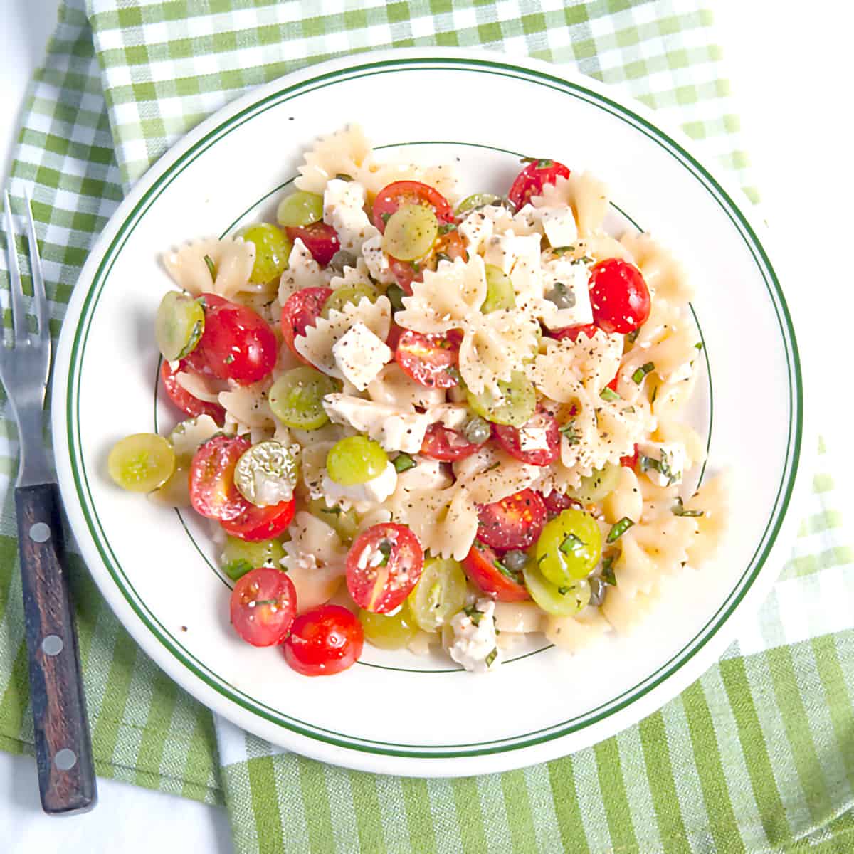 Bow Tie Pasta Salad with Tomatoes and Grapes - a surprising combination for a refreshing summery pasta salad. Great for a cookout or picnic! https://www.lanascooking.com/bow-tie-pasta-salad-with-tomatoes-and-grapes/