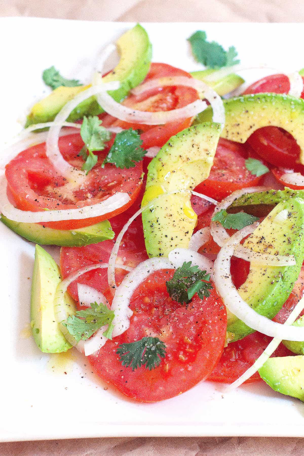 Tomato and avocado salad on a large white serving plate.