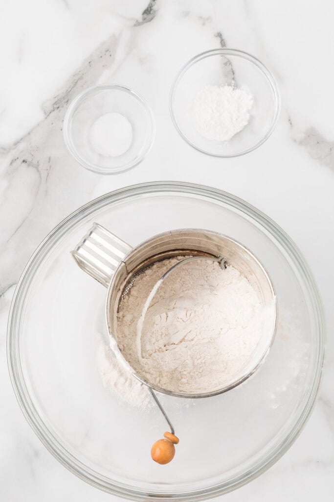 Sifting dry ingredients into a mixing bowl.
