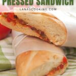 A Mediterranean pressed sandwich cut in half, wrapped in paper, and placed on a green checkered cloth.