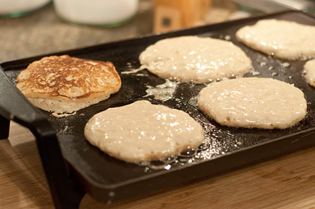 Pancakes cooking on a griddle.