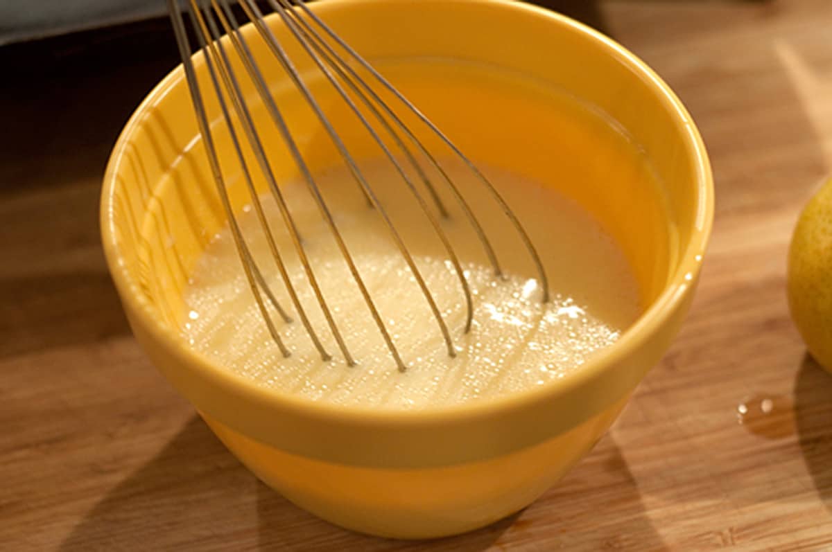 Wet ingredients and a whisk in a mixing bowl.