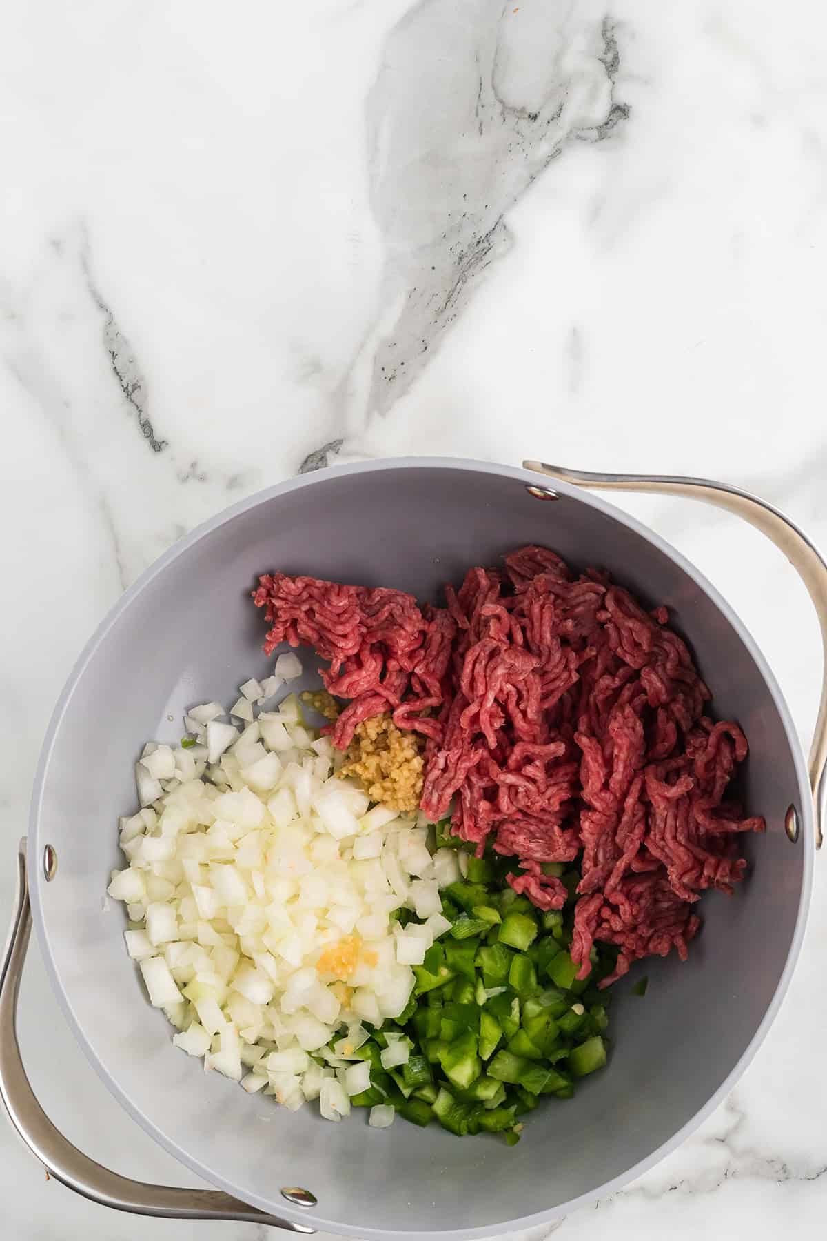 Olive oil, ground beef, and vegetables in a Dutch oven.