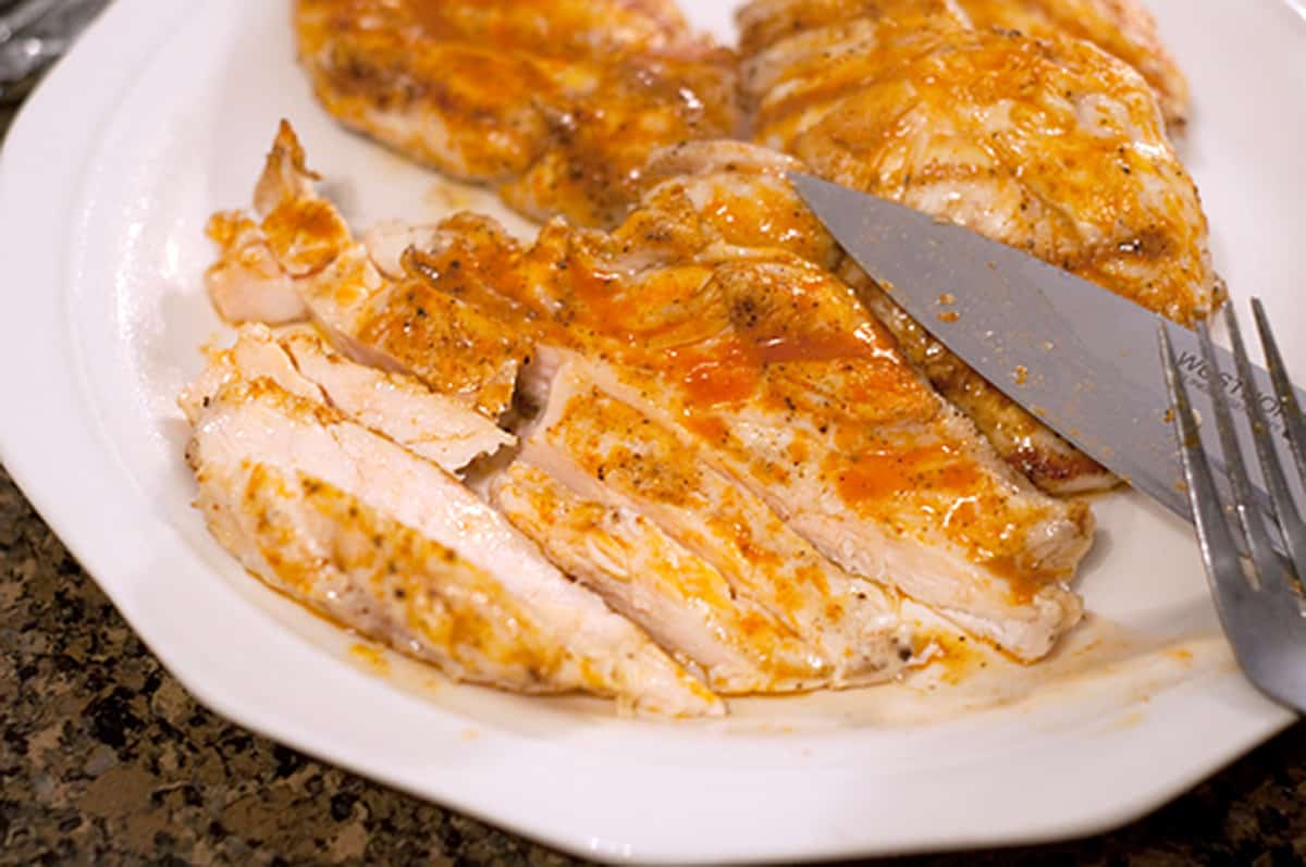 Slicing cooked chicken breasts.
