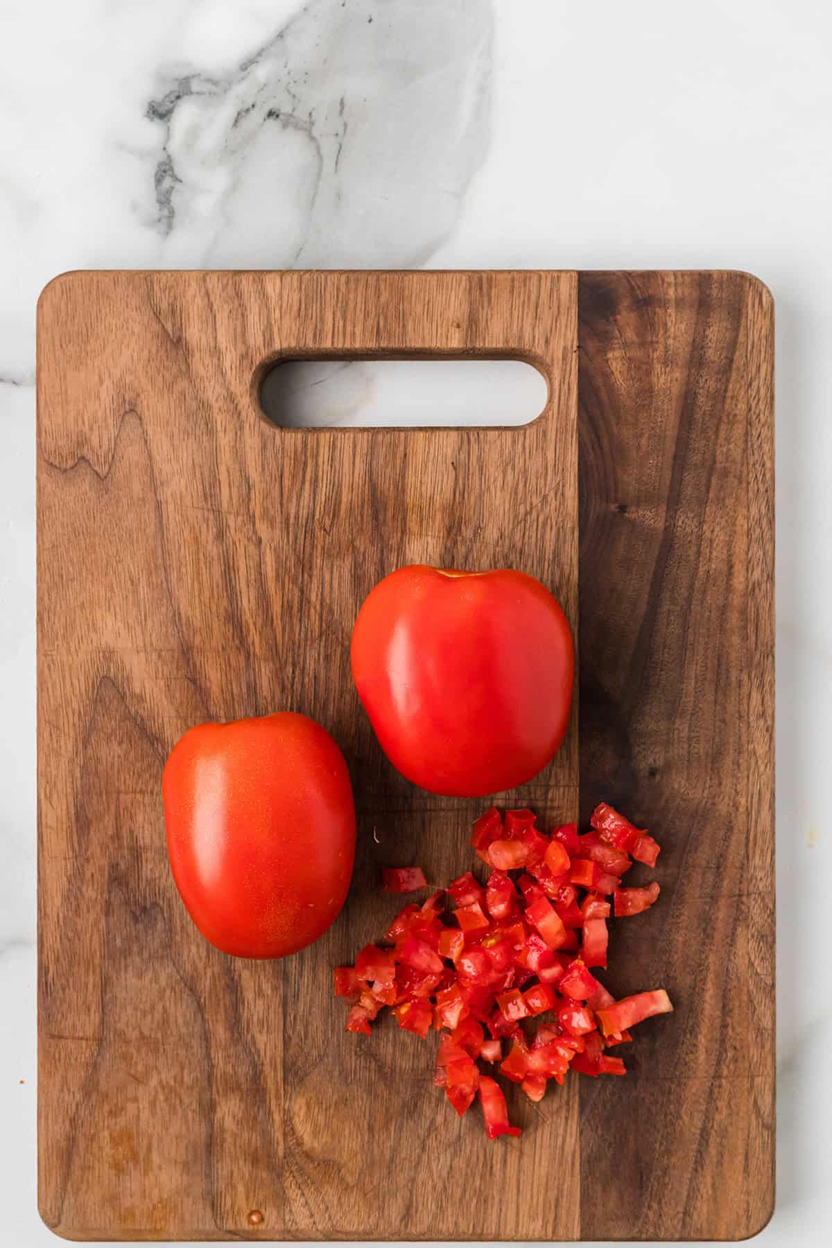 Chopped tomato on a wooden chopping board.