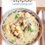A serving of oyster stew in a bowl with a napkin and spoon alongside. Text overlay for pinning.