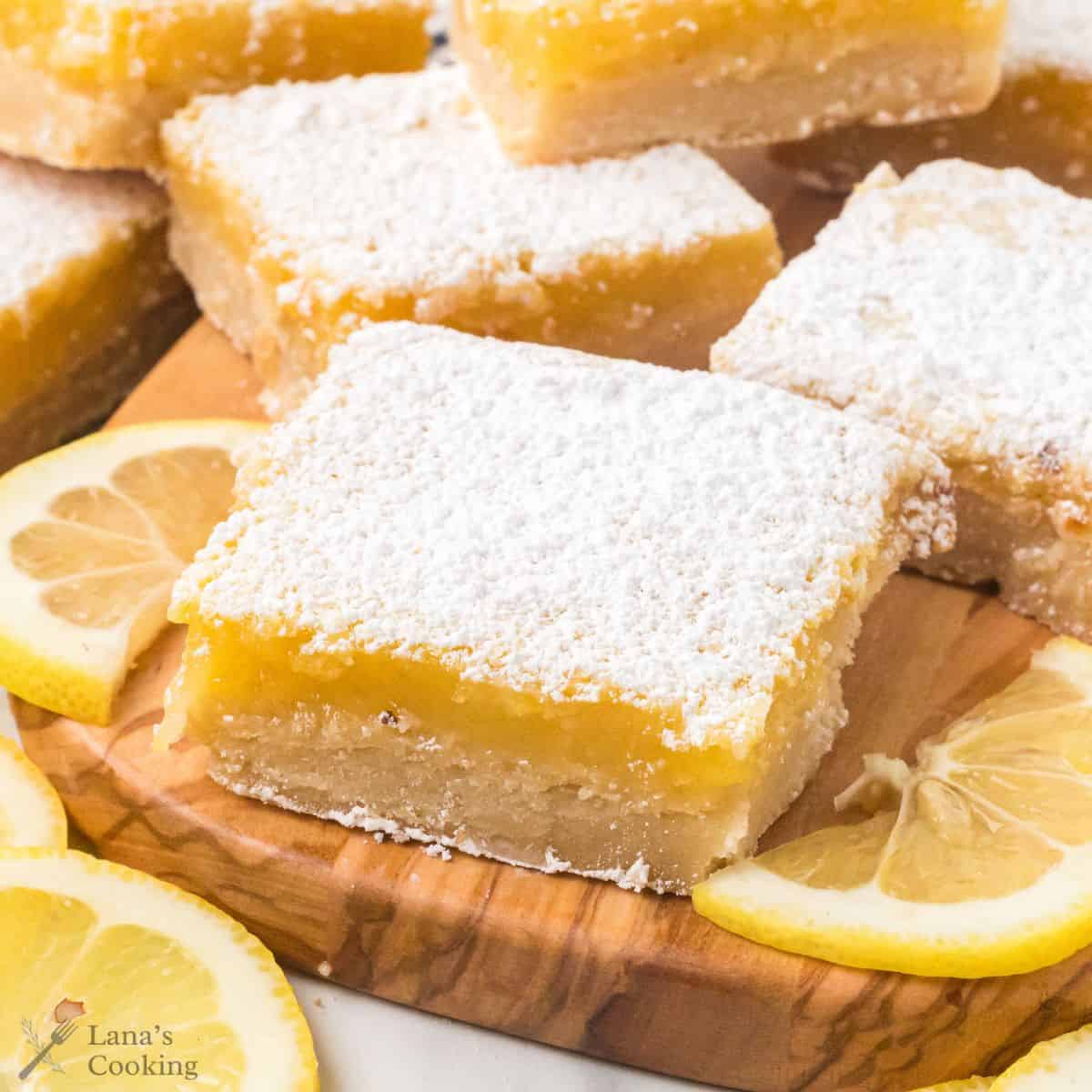 Lemon bars on a cutting board with lemon slices for decoration.
