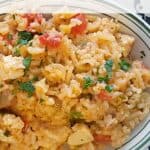 A bowl of red rice with tomatoes and herbs, topped with chopped parsley. Text: Red Rice Recipe, lanascooking.com.