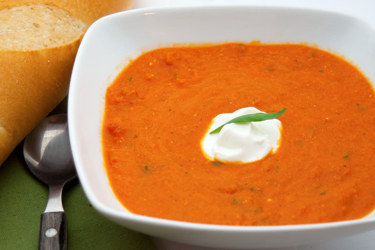 A serving of tomato tarragon soup in a white bowl.