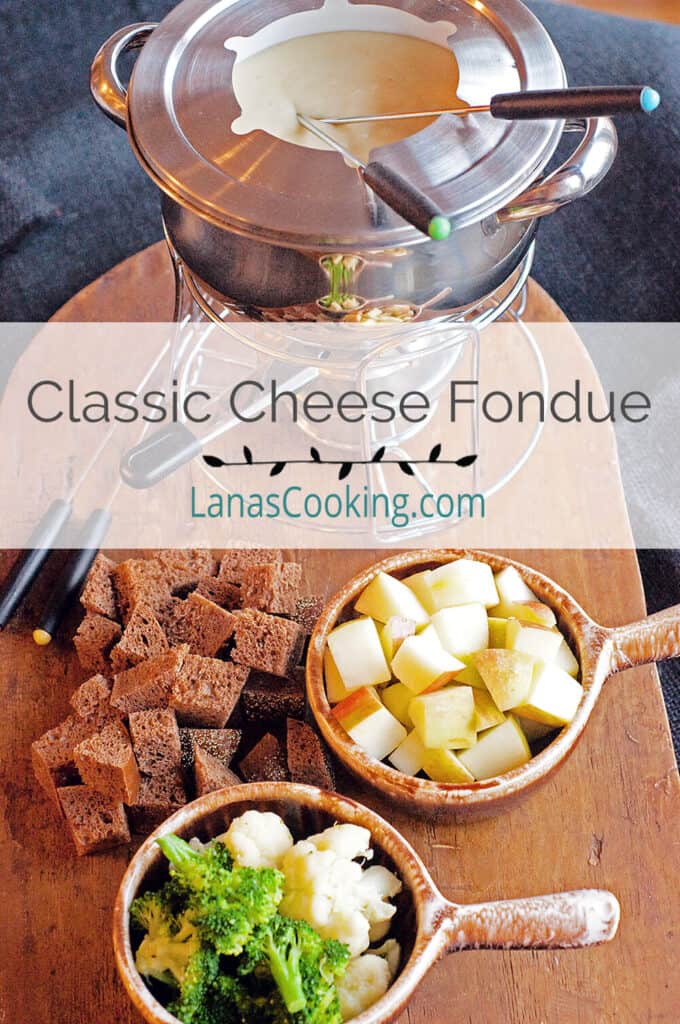 Cheese fondue in pot with bread and vegetable dippers.