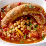 Italian sausage and white beans in a serving bowl.