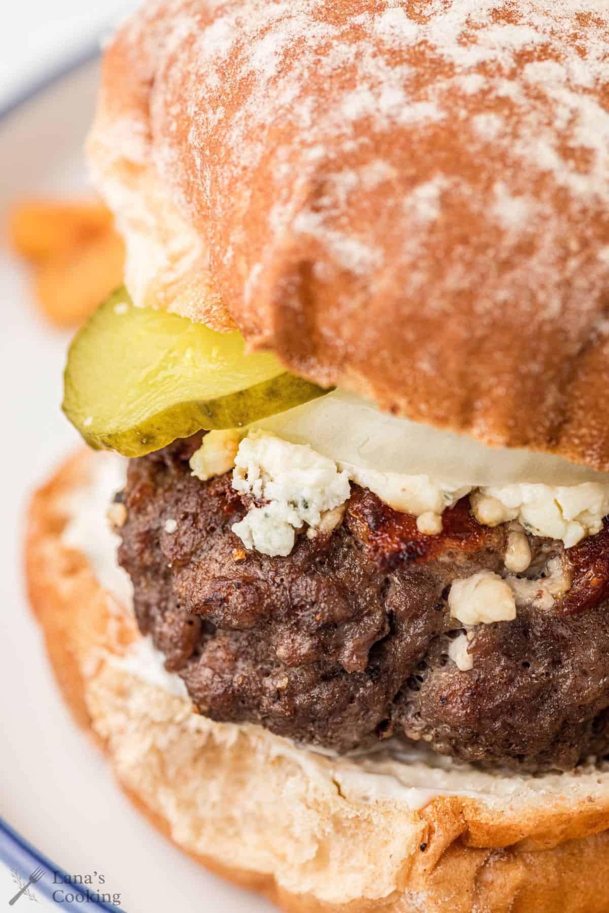 Bacon cheeseburger with pickle slices and blue cheese.