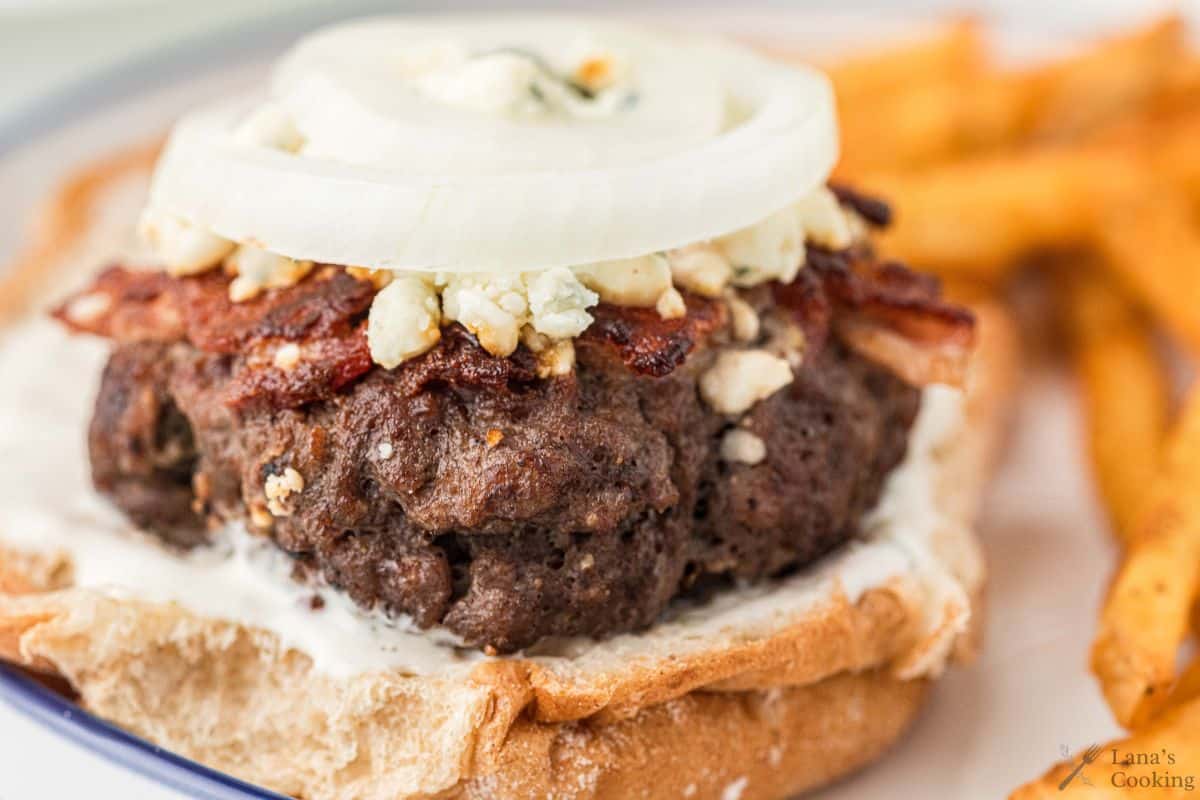 Bacon cheeseburger with blue cheese and sliced onion on top.