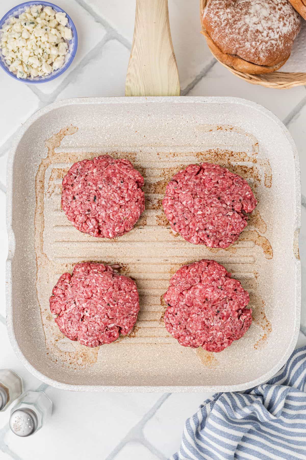 Burger patties placed bacon-side down in a grill pan.