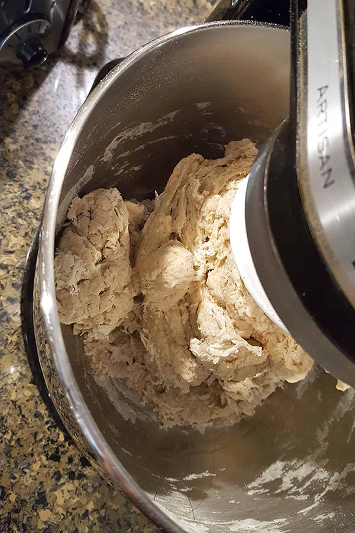 Dough being mixed in a stainless steel stand mixer bowl.