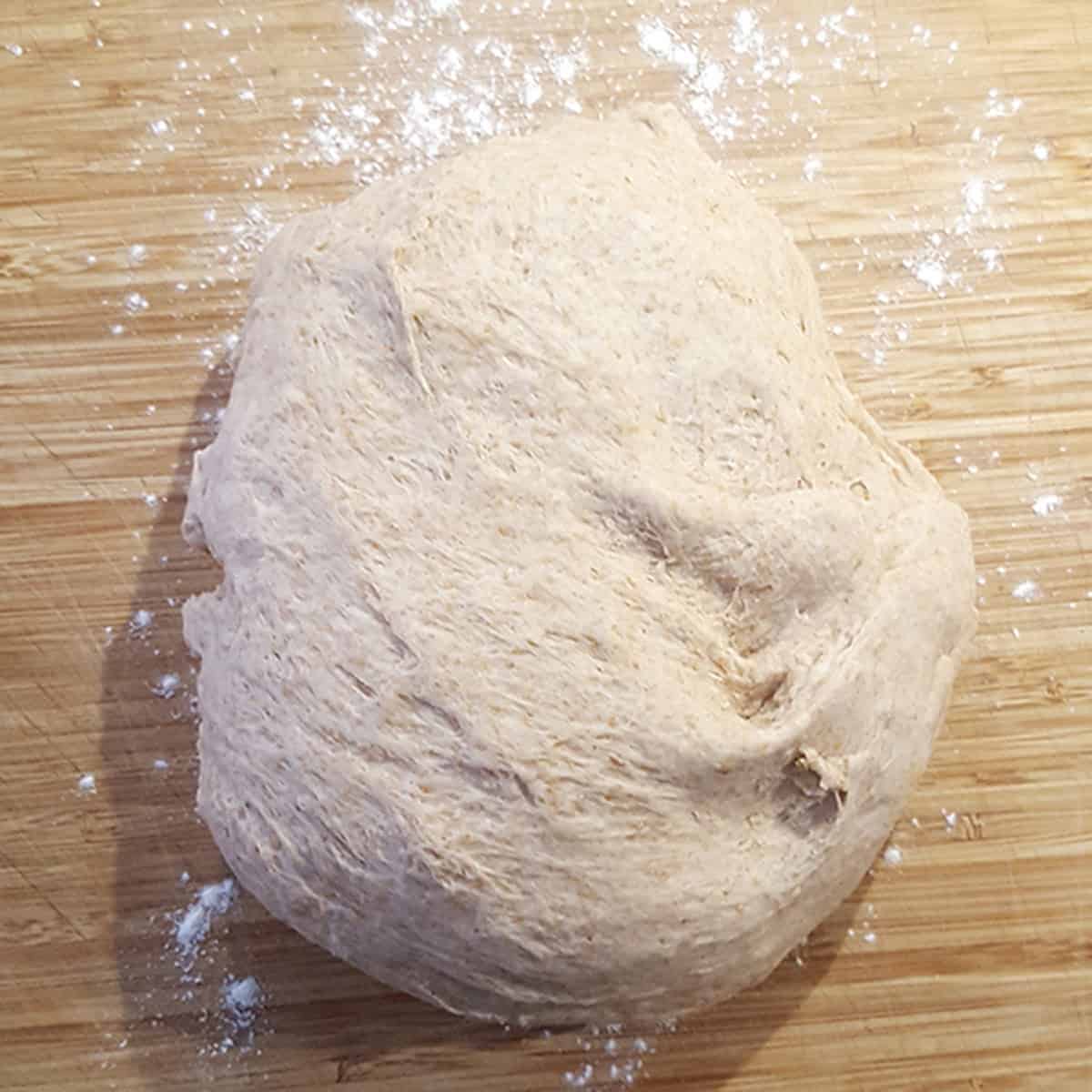 A ball of dough on a floured wooden surface.