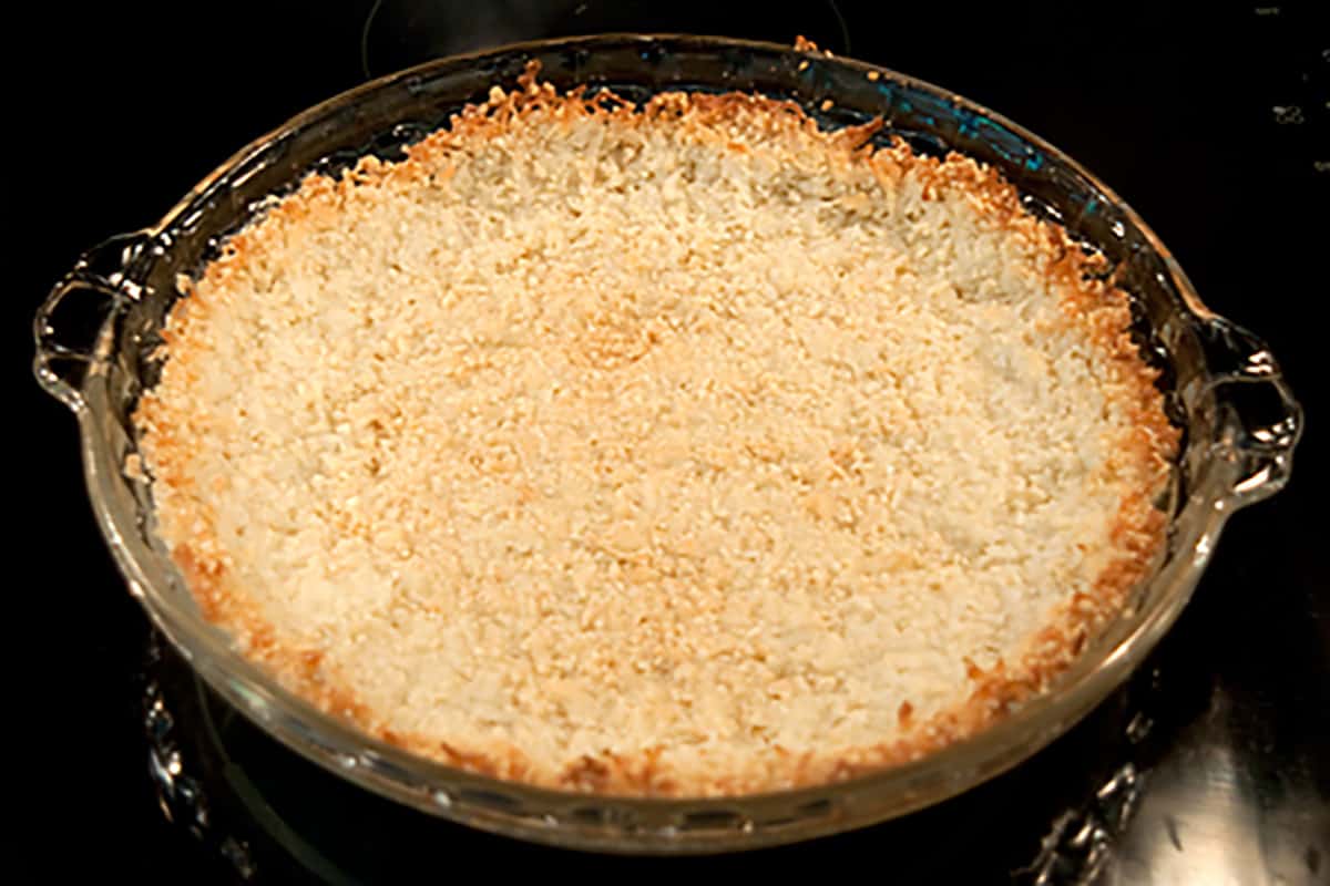 Almond and coconut pie crust Baked pie crust in a glass dish.