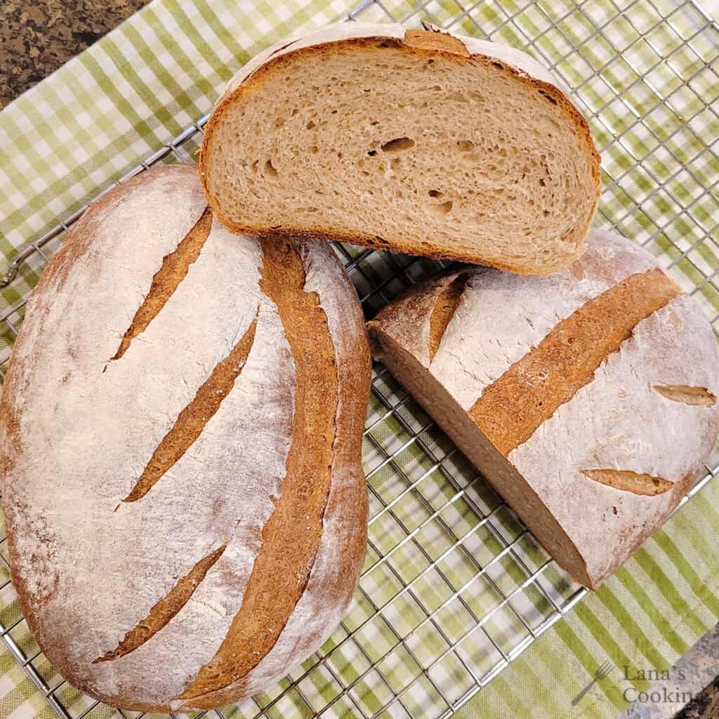 Two loaves of whole wheat sourdough bread on a kitchen towel.
