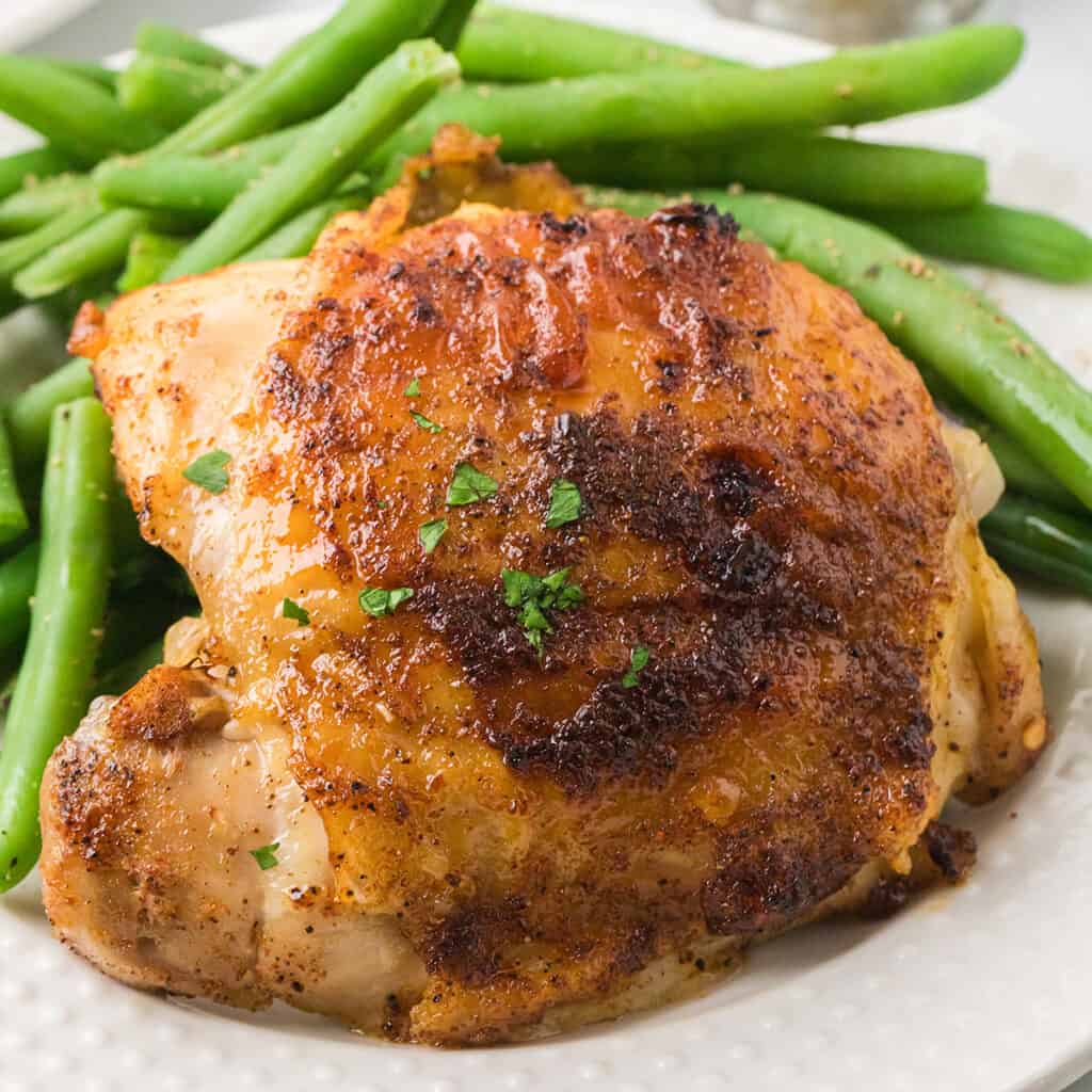 A serving of chicken with green beans on the side.