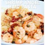 A plate of Mediterranean shrimp angel hair pasta garnished with herbs and vegetables.
