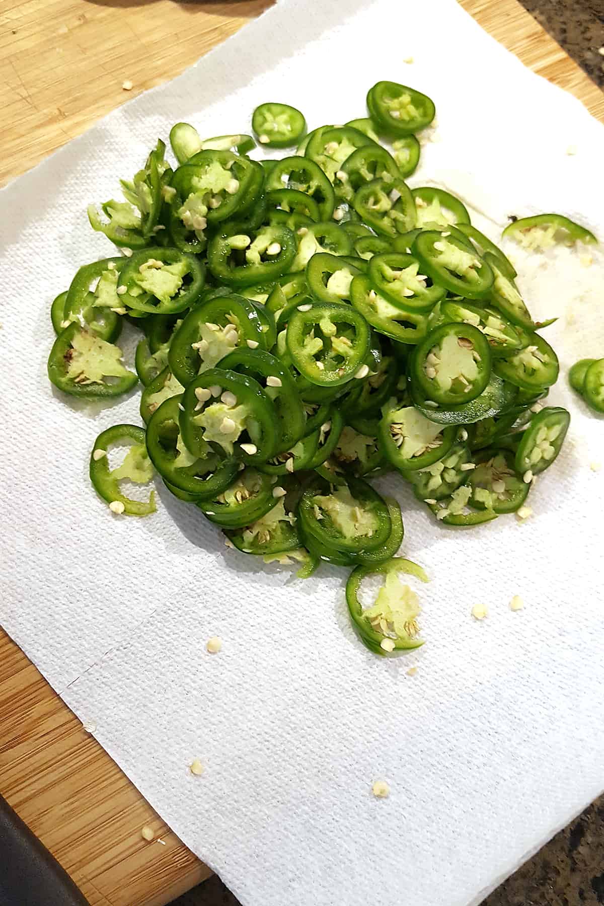 Thinly sliced jalapeno pepper rings on a paper towel.