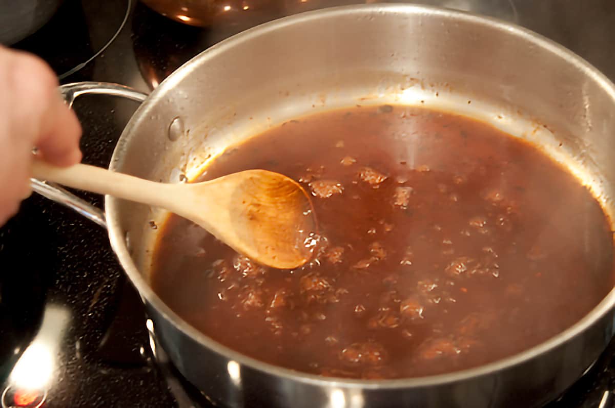 Red-Eye Gravy A wooden spoon stirring gravy in skillet