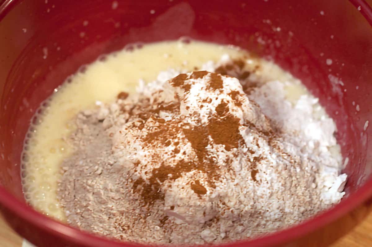 Flour, baking powder, baking soda, and cinnamon in a mixing bowl.