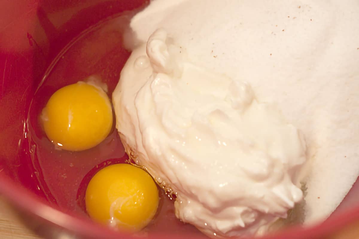 Sour cream, sugar, eggs, and vanilla in a mixing bowl.