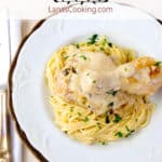 A serving of parmesan chicken and pasta on a dinner plate.