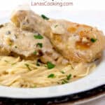 A serving of parmesan chicken and pasta on a dinner plate.