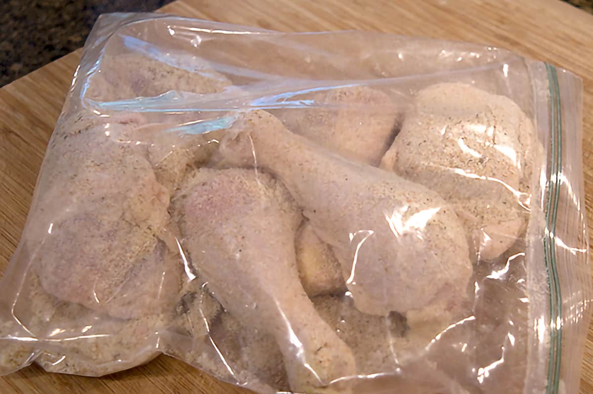 Chicken pieces covered with coating mix inside a plastic bag.