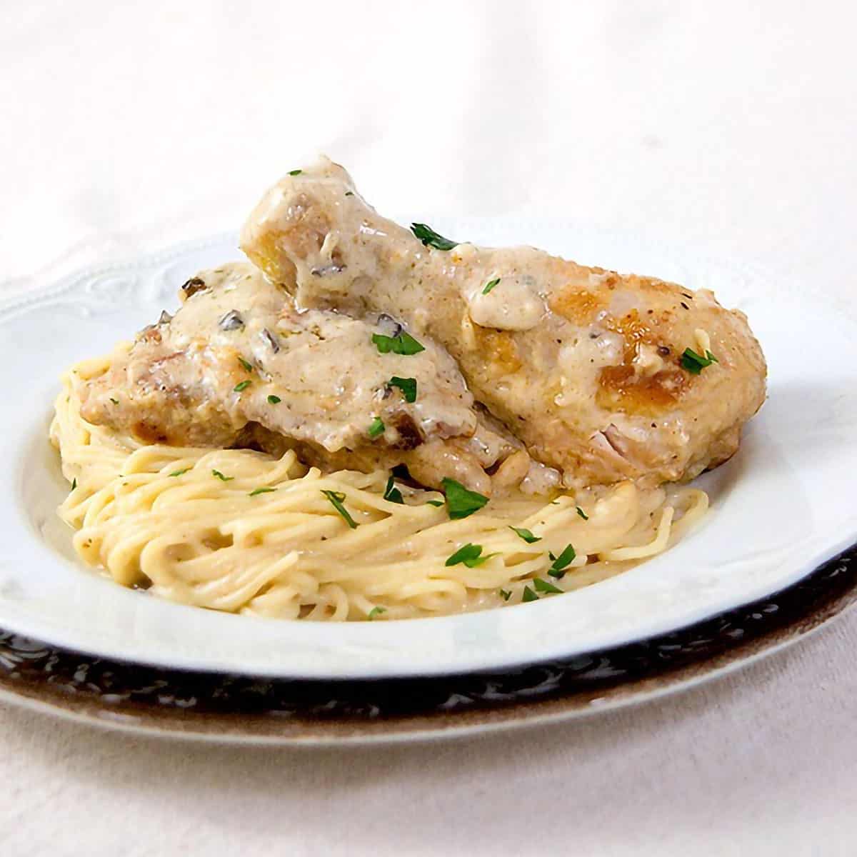 A serving of Parmesan chicken and pasta on a dinner plate.