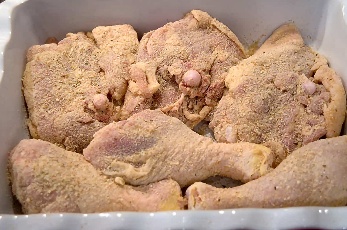 Coated chicken pieces ready to cook in a baking dish.