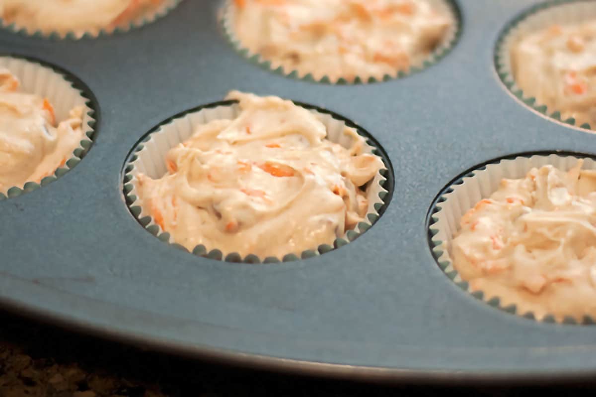 Close up view of muffin tin cups filled with cupcake batter.