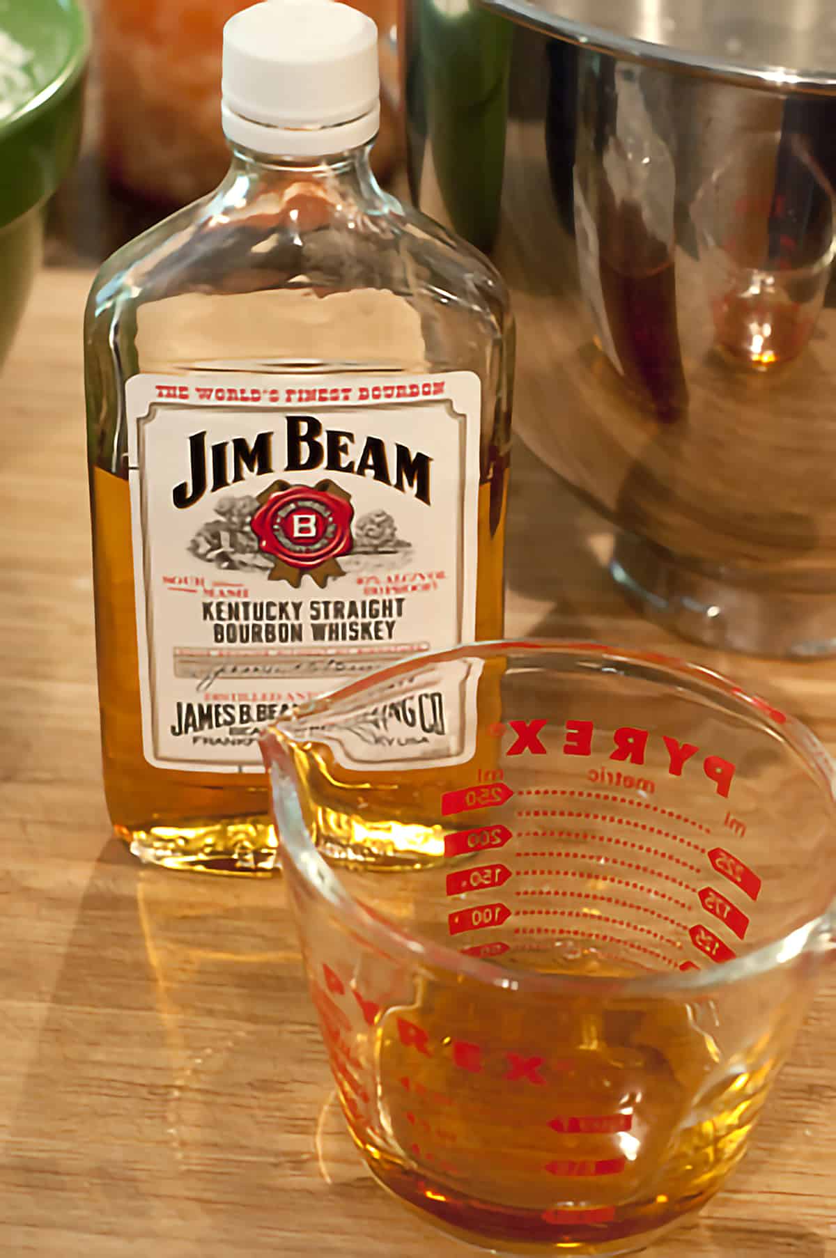 A bottle of Jim Beam Straight Bourbon Whiskey and a measuring cup containing whiskey for the recipe.