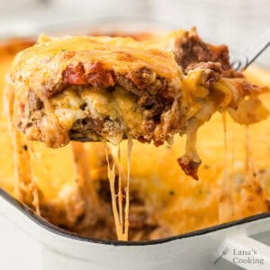 A spoon of egg noodle lasagna with stretchy cheese.