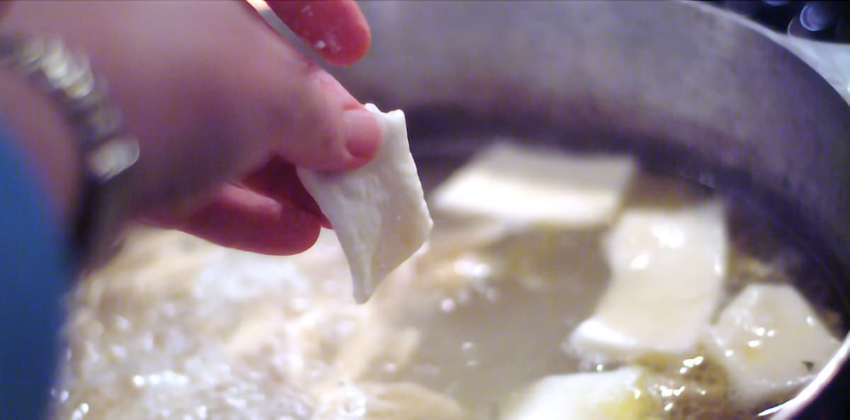 Dropping dumplings into the chicken broth.